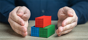 A person using their hands to protect miniature shipping containers.