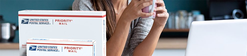 Woman sitting with coffee cup behind a Priority Mail box.