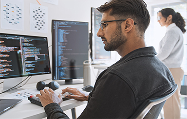Image of a person looking at computer code on a monitor.